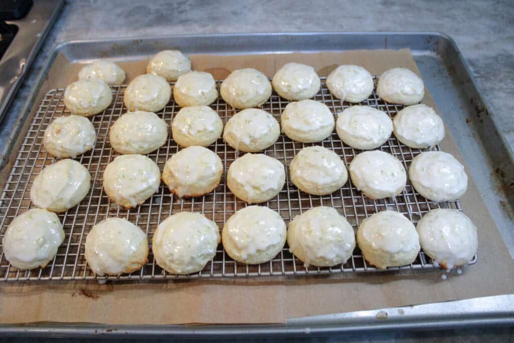 Freshly glazed Key Lime Ricotta Cookies cooling on a wire rack after baking.